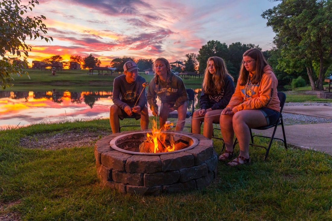 Four people surrounding a fire pit