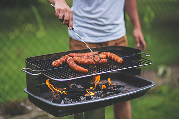 Man grilling sausage outside