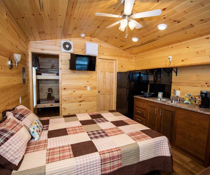 Boo Boo Two Room Cabin interior with queen-size bed, TV, ceiling fan, refrigerator, microwave, stovetop, sink, coffeemaker, and toaster