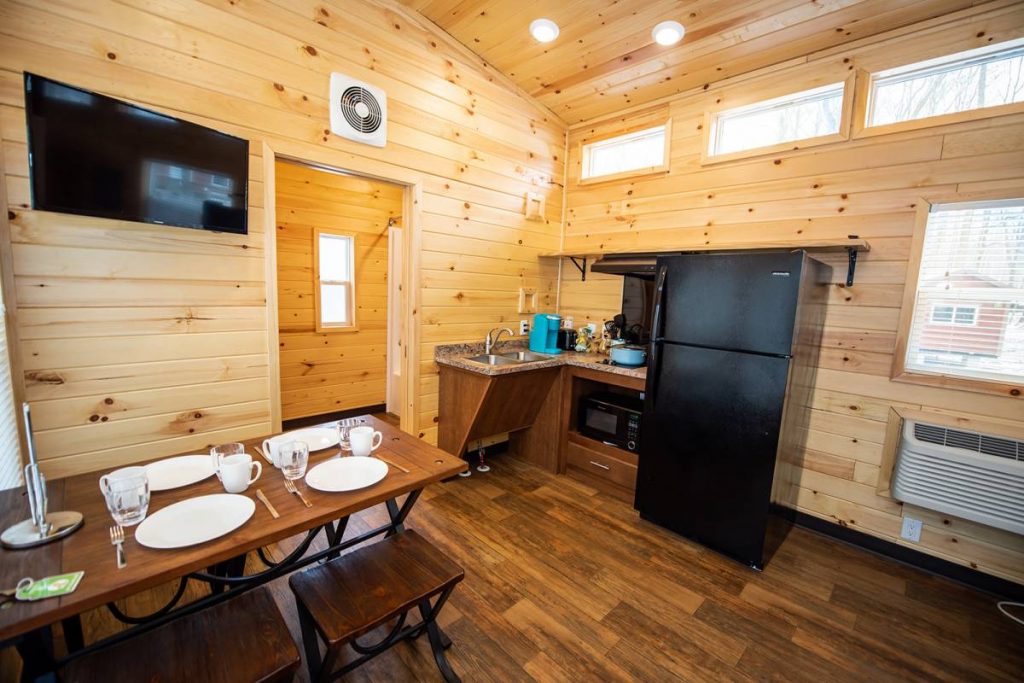 Cindy Bear™ Loft Cabin Dining Area with dishes, TV, refrigerator, sink, stovetop, and microwave
