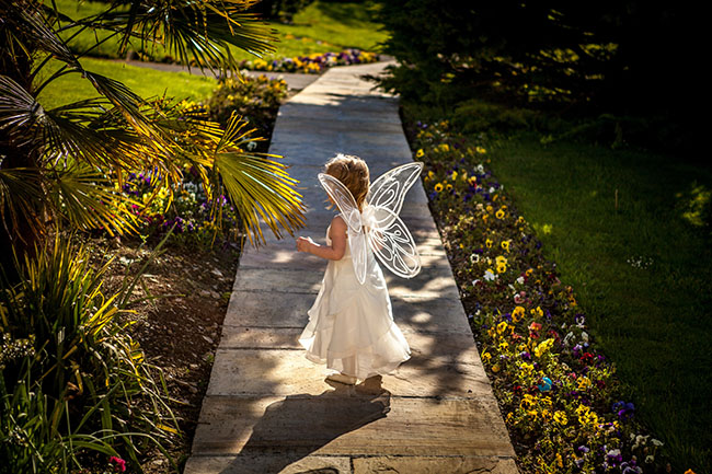 Small child dressed as fairy in a garden
