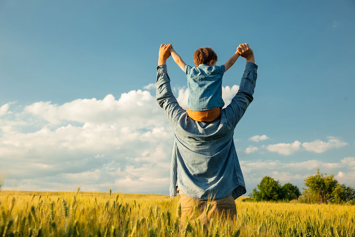 Father and child stretching arms up in field