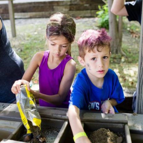 Two children panning for gold, one with face paint or sticker