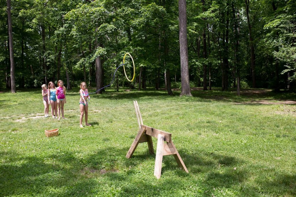 Children in forest tossing a hoop at a target from a distance