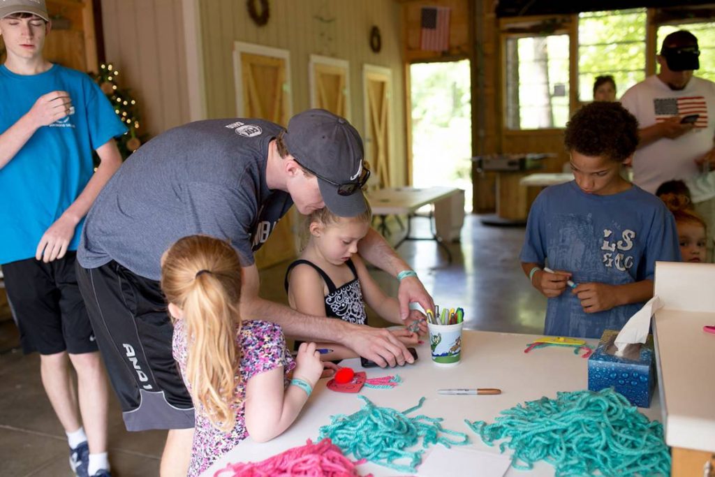 Children working on arts and crafts with adult assisting
