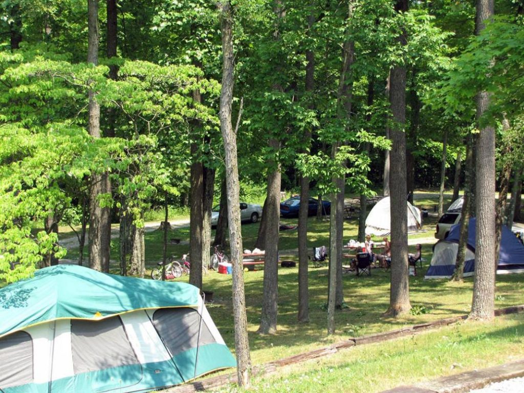Large camping area with tents and campers sitting in chairs