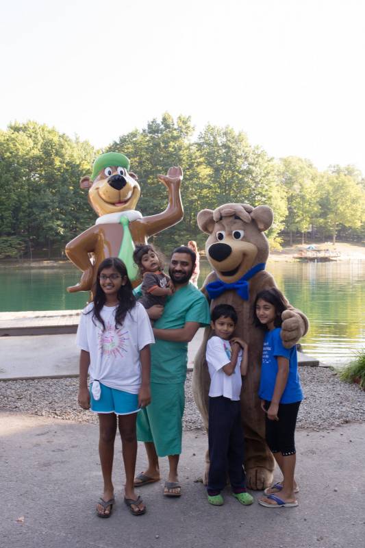 A family happily posing with a bear mascot