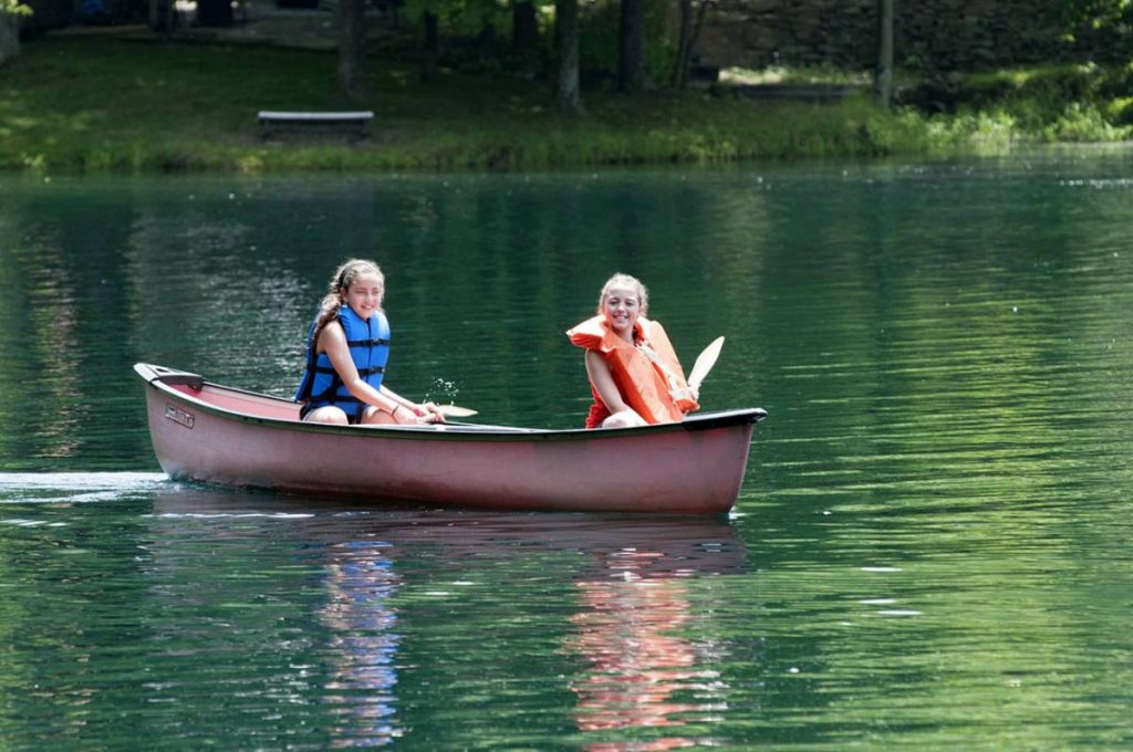 Two girls in a small boat on the lake, smiling