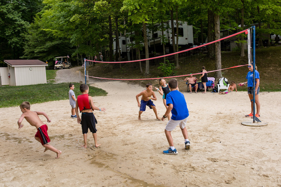Children playing a supervised game on a sandy volleyball court